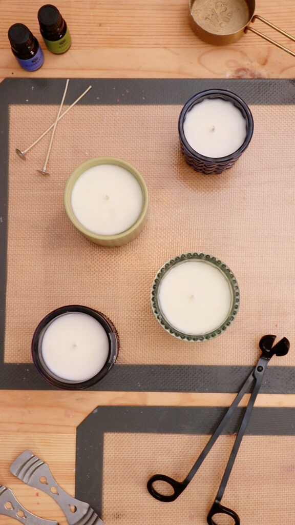 overhead-view-of-four-candles-on-table-surrounded-by-candle-making-supplies