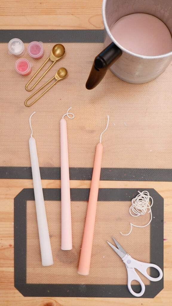 overhead-view-of-three-pink-taper-candles-on-table-with-candle-making-supplies