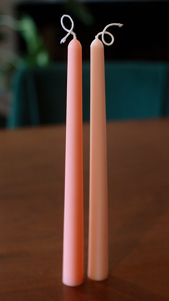 two-pink-taper-candles-on-wooden-table