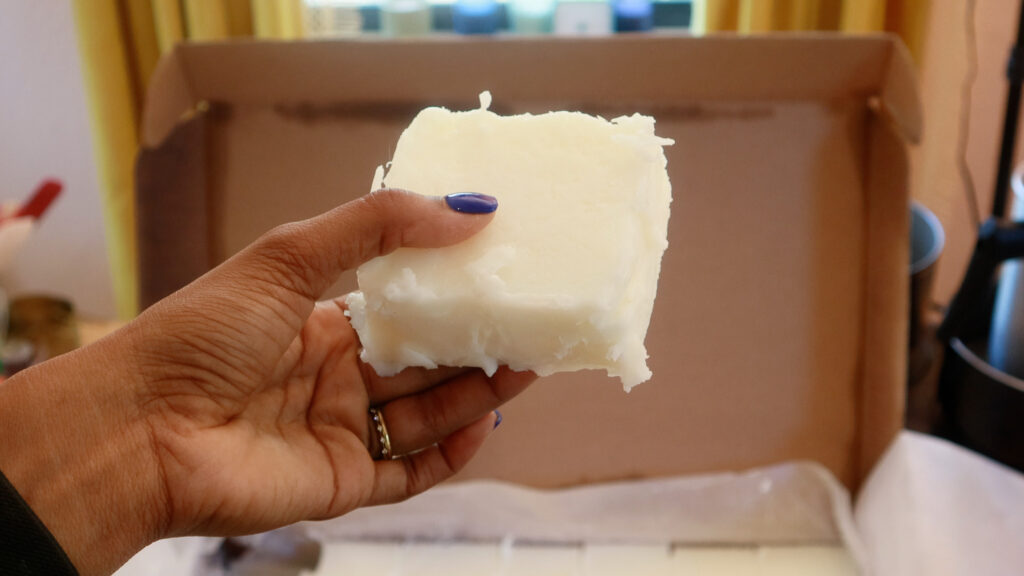 hand-holding-a-block-of-coconut-apricot-wax-for-candle-making