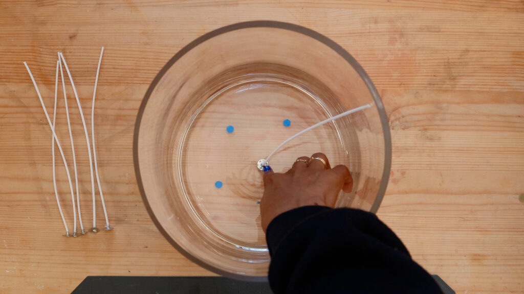 hand-attaching-candle-wick-to-bottom-of-candle-jar