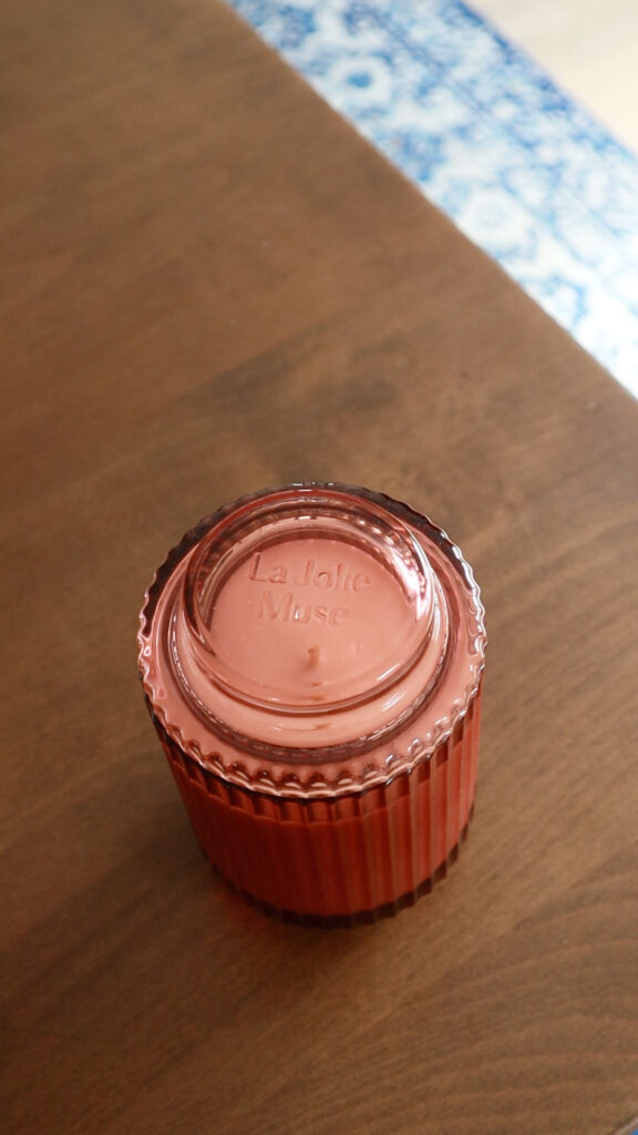 Overhead view of a pink glass La Jolie Muse Santal Rose candle jar.