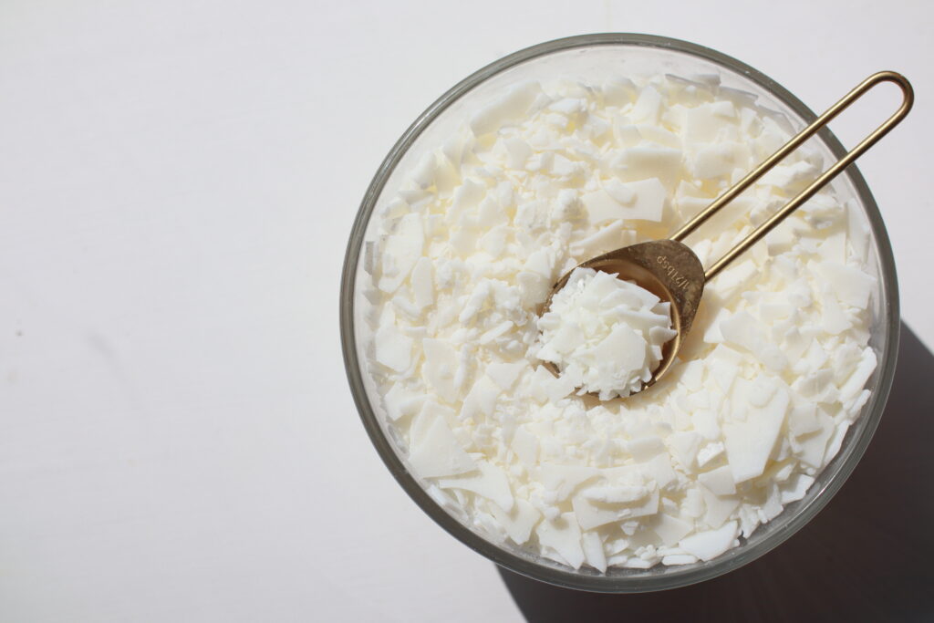 White soy wax flakes in a glass bowl.