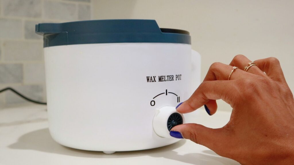 Hand turning on the heat on a wax melter pot.