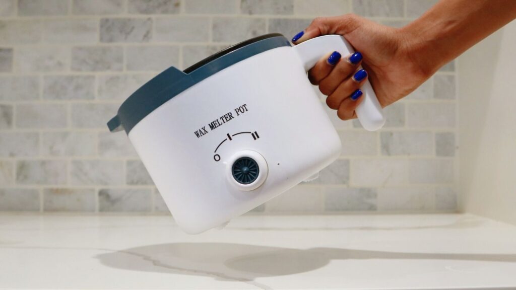Hand holding a wax melter pot.