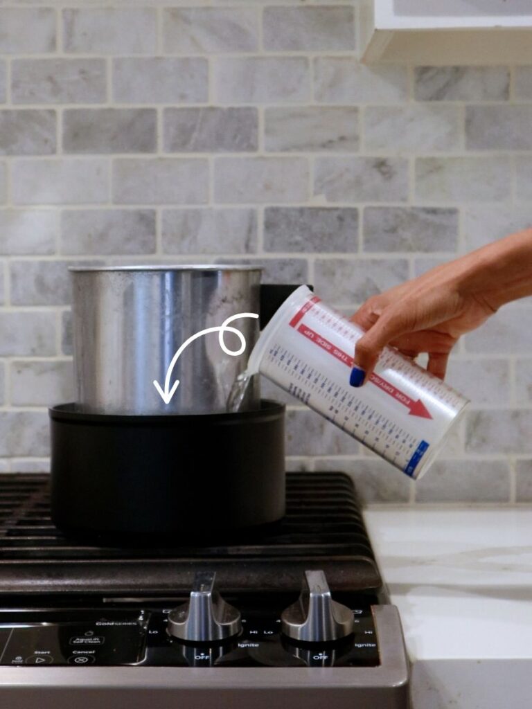 Pouring water into a double boiler for melting candle wax.