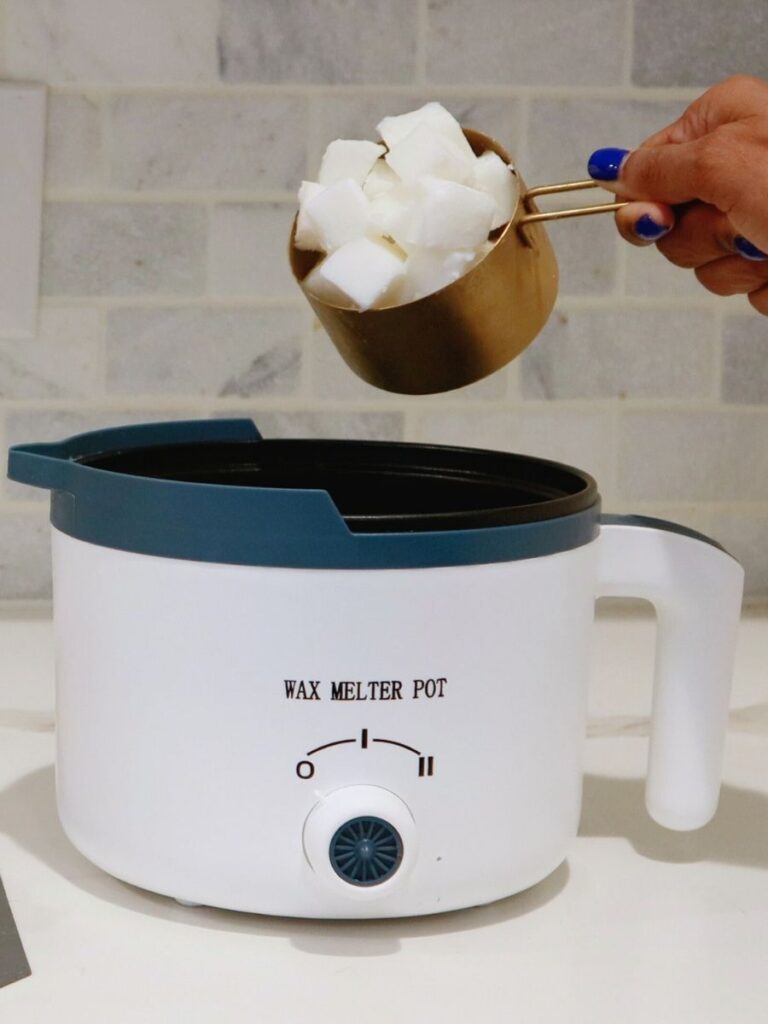 Hand pouring wax into a wax melter pot.